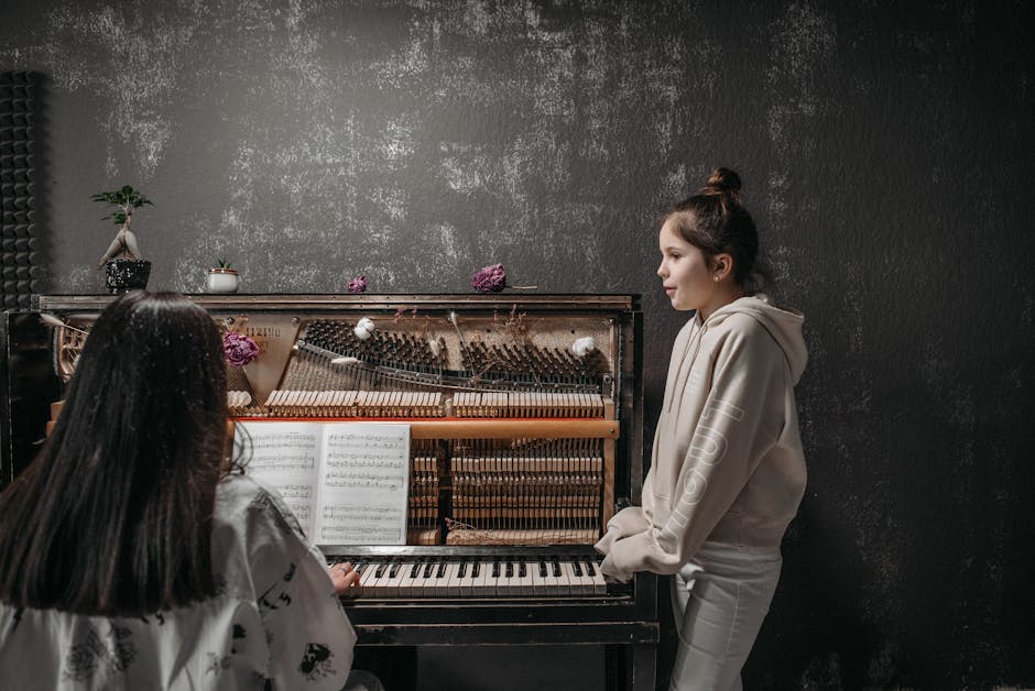 A young girl receiving piano lessons with a teacher in a music studio setting.